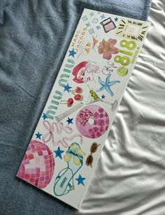 an open book laying on top of a bed covered in white sheets and colorful stickers