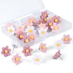 several pink and white flowers are in a plastic container next to each other on a white surface