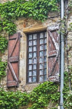 an old building with ivy growing on it's walls and shutters that are open