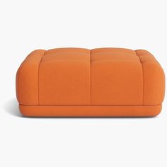 an orange ottoman sitting on top of a white floor