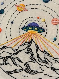 the embroidery design shows an alien flying through space with planets and stars in the background