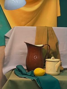 a pitcher, lemon and teapot sit on a table next to a cloth draped over it