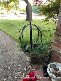 two planters with plants in them sitting on the ground next to a brick wall