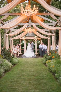 a bride and groom standing under a gazebo with their wedding party in the background