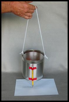 a hand holding a metal bucket with a yellow stick sticking out of the top and hanging from it