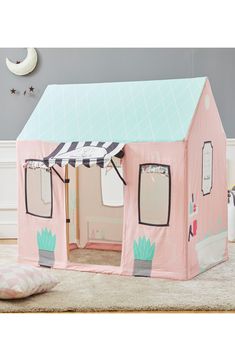 a pink play house with windows and doors on the outside, has an awning over it