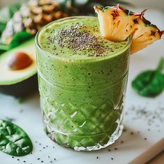 a green smoothie is garnished with an avocado and sprinkles