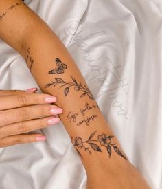 a woman's arm with flowers and butterflies on it, while she is laying down