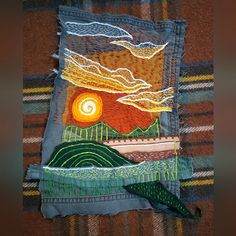 a piece of art made out of jeans and fabric with an image of a sunset on it