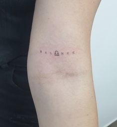 a woman's arm with the word balance tattooed on her left side, in small font