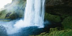 a large waterfall with green moss growing on the side