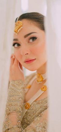 a woman wearing a gold head piece and holding her hand near her face