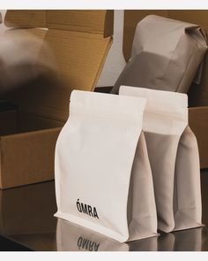 three bags sitting on top of a table next to some boxes and paper bag with the word omra written on it