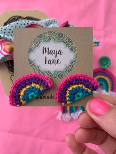 a person holding up a card with two colorful crocheted pieces on it and the words maya lane