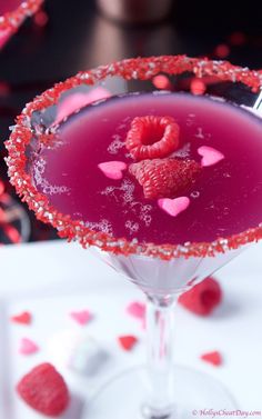 a red drink in a martini glass with hearts on the rim and garnishes