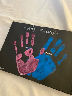 a child's hand and foot print on a black canvas with pink and blue ink