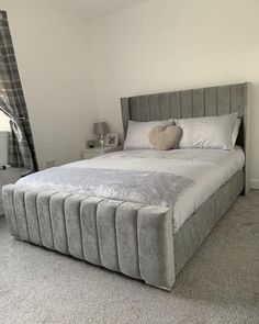 a large bed sitting in the middle of a bedroom next to a window with curtains