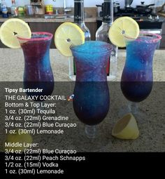 three glasses filled with blue liquid and lemons sitting on top of a kitchen counter