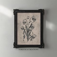 a black frame hanging on the wall with flowers in it