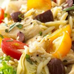 pasta salad with chicken, tomatoes, and olives on a white plate close up