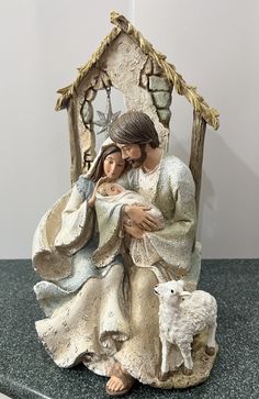 a statue of jesus holding a baby jesus in his arms and standing next to a sheep