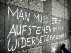 graffiti written on the side of a wall in german language, with stars and an arrow