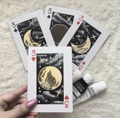 four playing cards with an image of the moon and stars on them are being held by a woman's hand