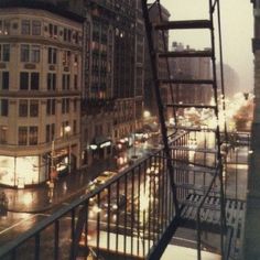 a city street filled with lots of traffic next to tall buildings at night and rain falling on the ground