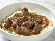 a bowl filled with meat and gravy on top of mashed potatoes