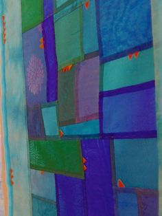 a quilted wall hanging with blue, green and purple squares on the bottom half