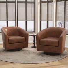 two brown leather chairs sitting on top of a rug in a living room next to windows