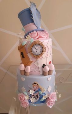 a three tiered cake decorated with pink and blue decorations, including a clock on top