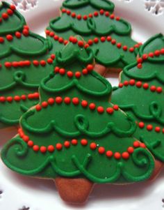 decorated cookies on a white plate with red beads and green trees in the middle,