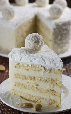 a slice of cake with white frosting and nuts on the top is sitting on a plate