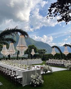 an outdoor wedding setup with chandeliers and tables set up for the guests to eat