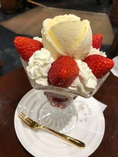 strawberries and whipped cream in a glass dish on a table