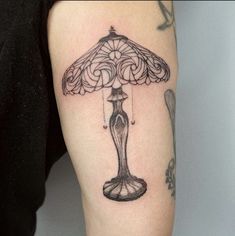 a woman's arm with a lamp tattoo on it