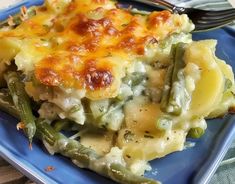 a blue plate topped with a casserole covered in green beans and cheese next to a fork