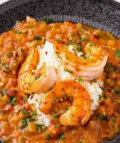 a black plate topped with shrimp and rice