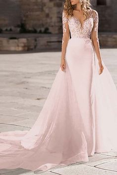 a woman in a pink wedding dress standing on a stone walkway with her back to the camera