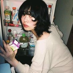 a woman is looking in the refrigerator with her hand on an empty carton box