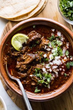 a bowl filled with beef and onions next to tortilla bread on a cutting board