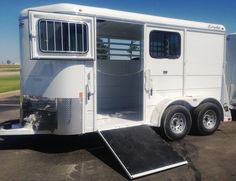 a white horse trailer parked in a parking lot