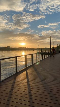 the sun is setting over the water and boardwalks in front of a body of water