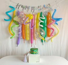 balloons and streamers are hanging on the wall next to a table with a cake