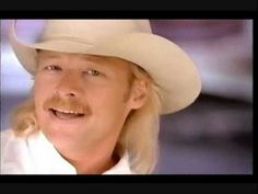 a man wearing a white cowboy hat with long blonde hair and a moustache on his face