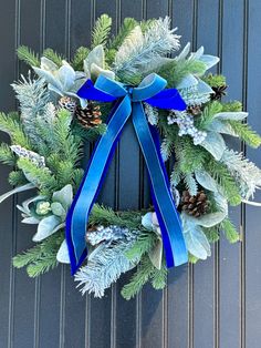 a wreath with blue ribbon and pine cones