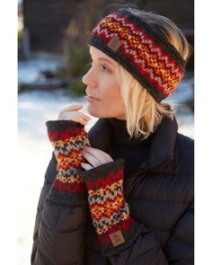 a woman wearing a knitted hat and mittens in the snow with her hand on her chin