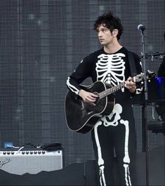 a man in skeleton suit playing guitar on stage