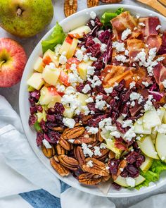 a salad with apples, cranberries, pecans and goat cheese on top